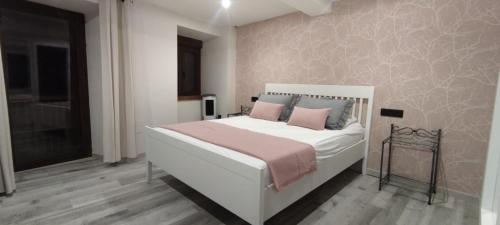a bedroom with a white bed with pink pillows at La Casita de Sofía in Monforte de Lemos