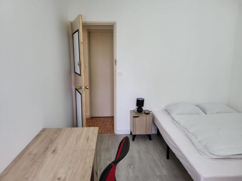 une chambre avec un lit et une table en bois dans l'établissement Chambre dans meublé tout équipé, à Angoulême