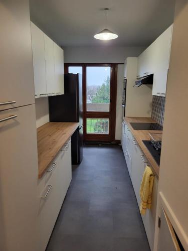 une cuisine avec des placards blancs et une grande fenêtre dans l'établissement Chambre dans meublé tout équipé, à Angoulême