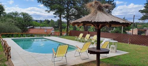 a group of chairs and an umbrella next to a pool at La Calma, casa frente al río, gran parque y pileta in Villa Icho Cruz