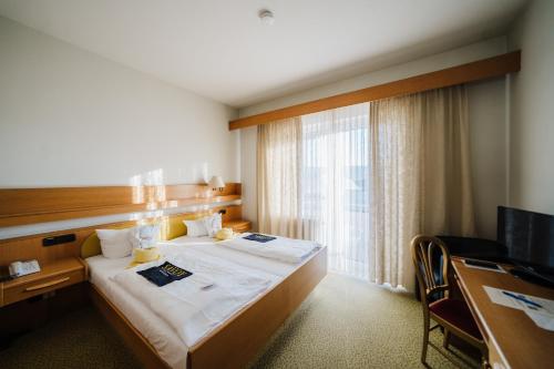 a hotel room with a bed and a desk and a window at Savoy Hotel Bad Mergentheim in Bad Mergentheim