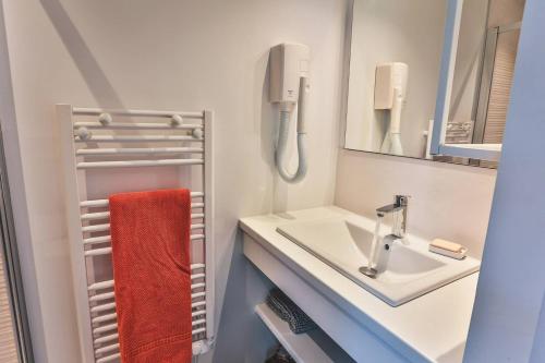 une salle de bain avec un lavabo et une serviette rouge dans l'établissement Villa CHEBEC Appartement en rez de jardin avec terrasse vue sur golf d Hossegor, à Hossegor