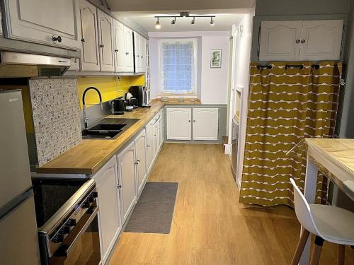 a kitchen with white cabinets and a counter top at Maison "La Butte" - Suisse Normande in Ségrie-Fontaine