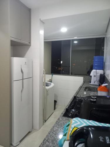 uma cozinha com um frigorífico branco e um fogão em Apartamento próximo ao centro com elevador! em Patos de Minas