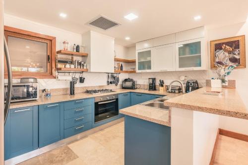 a large kitchen with blue cabinets and appliances at Villa with 3 bedrooms private pool and ocean view in Santa Bárbara de Samaná