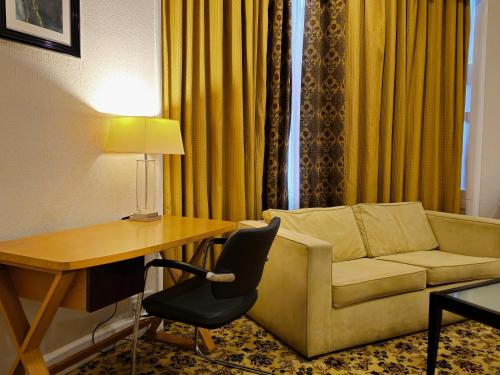 a living room with a couch and a table and a desk at Crown Hotel Stone in Stone