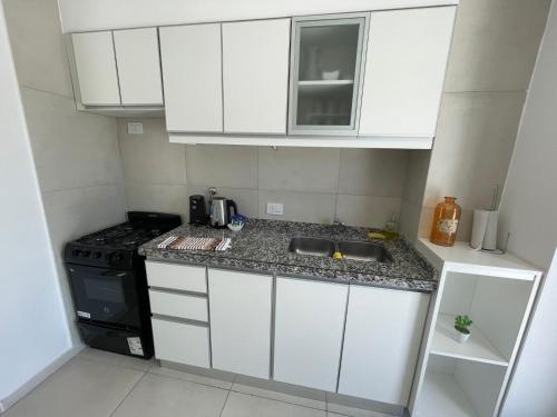 a small kitchen with white cabinets and a stove at Dpto nuevo Centro Cochera super Balcón Asador in Santa Fe