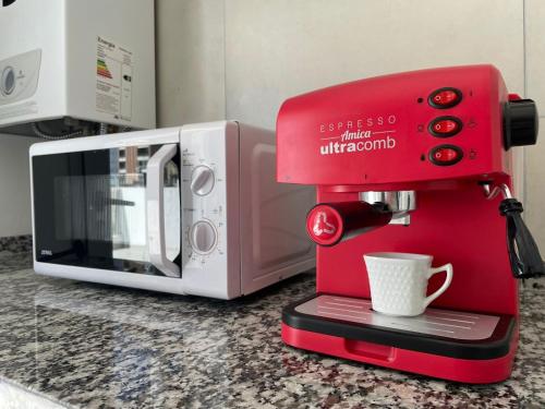 a red coffee maker sitting next to a microwave at Dpto nuevo Centro Cochera super Balcón Asador in Santa Fe