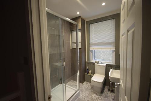 a bathroom with a shower and a toilet and a sink at Four Bedroom House Chandos Road in London