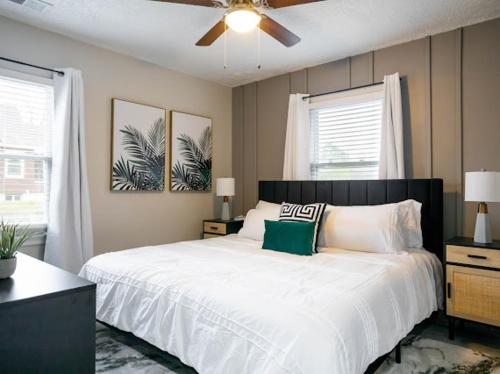 a bedroom with a white bed with a ceiling fan at Bluegrass Bungalow in Louisville
