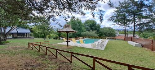 un patio trasero con piscina y valla en La Calma, casa frente al río, gran parque y pileta en Villa Icho Cruz