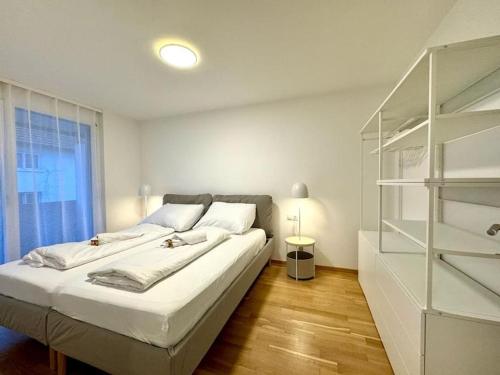 ein weißes Schlafzimmer mit einem großen Bett und einem Fenster in der Unterkunft For You Apartment in Dornbirn