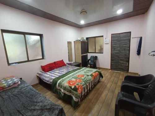 a bedroom with two beds and a chair at Gazebo Holiday Home in Srīvardhan