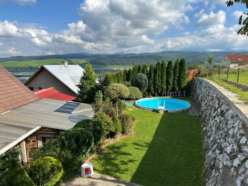a backyard with a swimming pool and a stone wall at Ubytovanie Privat Antoni - apartmán v RD in Tvrdošín