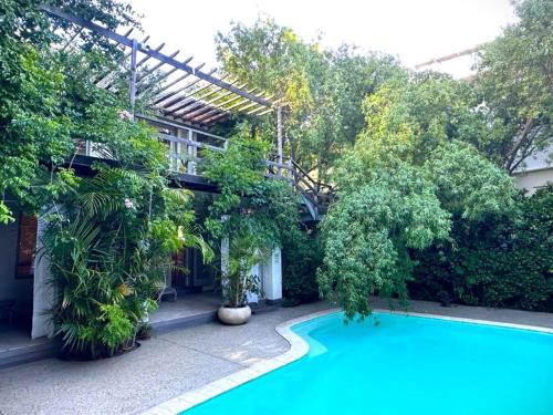 a swimming pool in front of a building with trees at Cape Standard Guest House in Cape Town