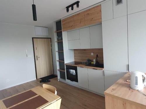 a kitchen with white cabinets and a wooden table at LUX Apartament Free Parking in Leszno