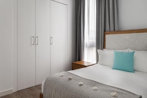 a bedroom with a white bed with a blue pillow at Residencias Cityzen cerca del Aeropuerto in Echeverría
