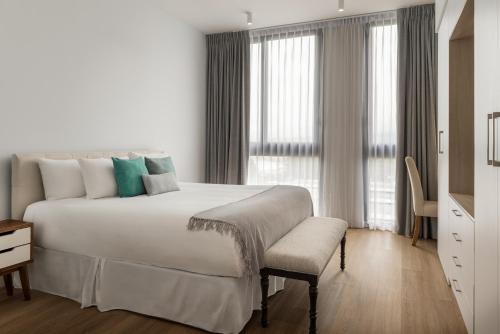 a white bedroom with a large bed and a window at Residencias Cityzen cerca del Aeropuerto in Echeverría