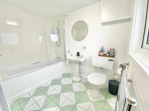 a bathroom with a sink and a toilet and a tub at Peninsula Cottage in Garrabost