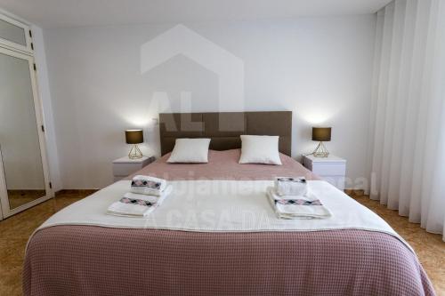 um quarto com uma cama grande com duas toalhas em Moinho D'ouro Residence by ACasaDasCasas na Ericeira