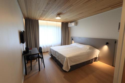 a bedroom with a bed and a desk and a window at Hotelli Heimari in Heimari