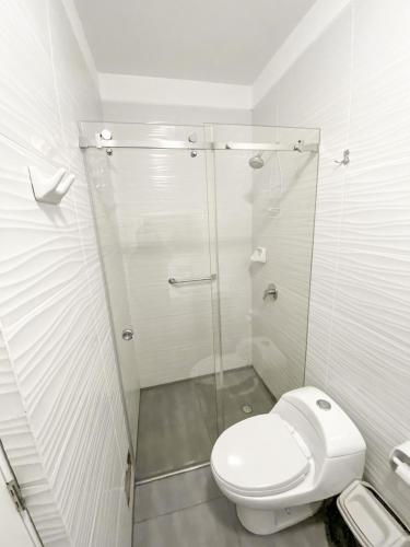 a bathroom with a toilet and a glass shower at TRIPLEX en San Bartolo Las Olas Reservas in San Bartolo