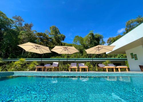 a swimming pool with chairs and umbrellas at Luxury Apartments Nauyaca by Paradiselodge in Platanillo