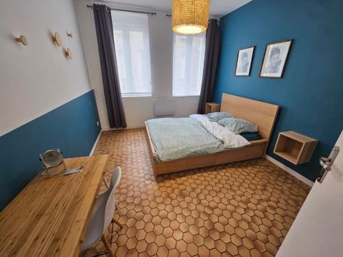 een slaapkamer met een bed en een houten tafel bij L'olivier in Douai