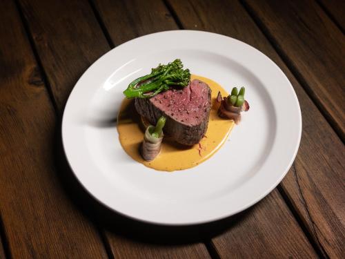 a white plate with a piece of steak on a table at Hotel Rozkoš in Česká Skalice