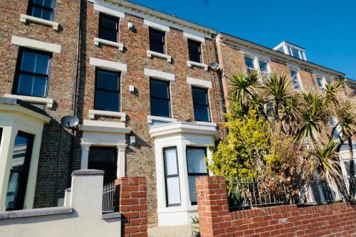 a brick building with a tree in front of it at Longsands Beach, Apartment 2, Tynemouth in Tynemouth