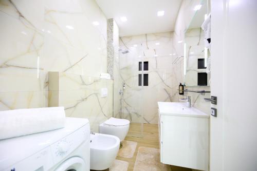 a white bathroom with a toilet and a sink at Jimi Apartments in Vlorë