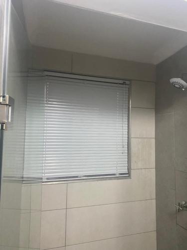a window with a blind in a bathroom at Studio house in Durban