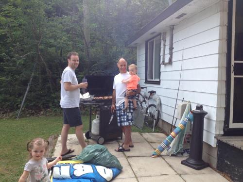 a group of people standing in a backyard with a grill at Little Hawk Resort & Marina in Algonquin Highlands