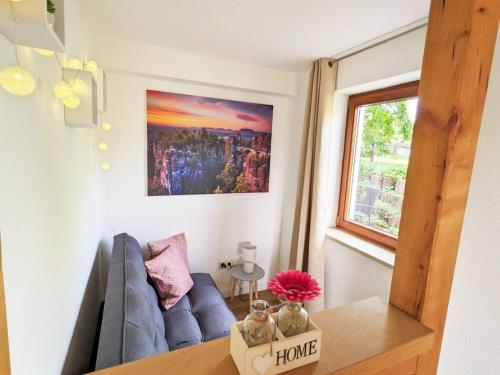 un salon avec un canapé bleu et une fenêtre dans l'établissement S2 - Urlaubsmagie - Am Wanderweg mit Terrasse, à Sebnitz