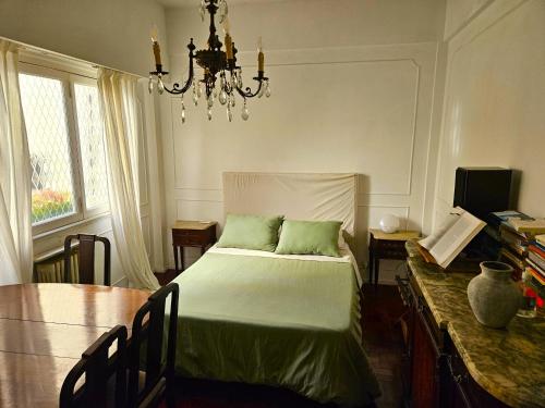 a bedroom with a bed and a table and a chandelier at A Friendly Room in the Heart of Recoleta -in Shared Apartment- in Buenos Aires