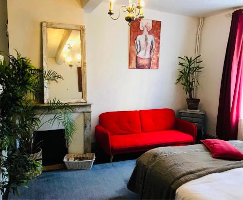 a living room with a red couch and a mirror at Mirepoix Labyrinthe chambre avec salle de bain et lit 180 cm in Mirepoix