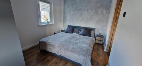 - une chambre avec un lit doté d'une couette bleue et d'une fenêtre dans l'établissement Apartament Karkonoski Zen z kominkiem pod Chojnikiem, à Jelenia Góra