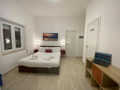 a bedroom with a bed and a laptop on a desk at Le casette di Frà Host and Go in Santa Severa