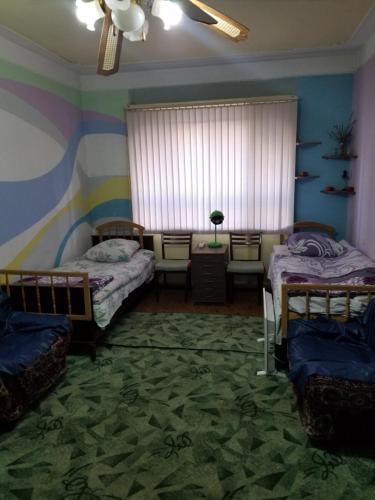 a bedroom with two beds and a window with a ceiling fan at Guest House Dompolski in Gyumri