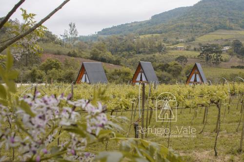 una fila de cabañas de madera en un campo con flores en Refúgio do Vale Cabanas Exclusivas en Bento Gonçalves