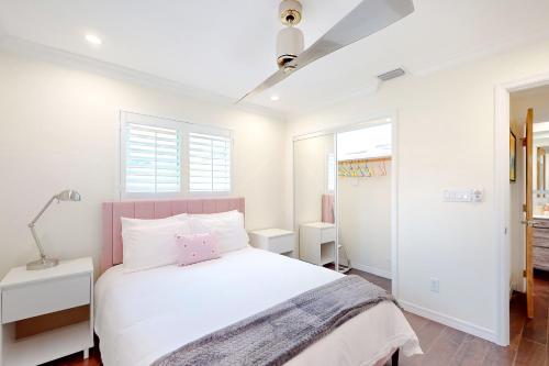 a white bedroom with a bed and two windows at Pink Flamingo in Naples