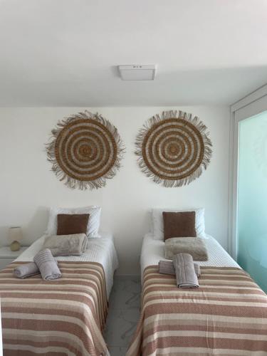 2 camas en una habitación con toallas y obras de arte en la pared en Appartamento Long Beach, en Punta del Este