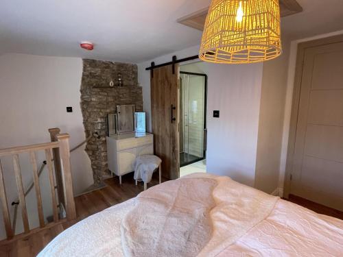 Charming 1-Bed Cottage in Brynmenyn في بريدجيند: غرفة نوم بسرير وجدار حجري
