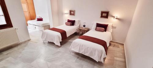 two beds in a room with white walls and tile floors at Vivienda con fines turísticos "Casa Paquita" in Andújar