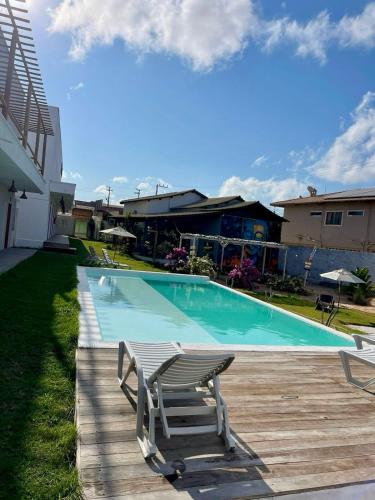 a swimming pool with two chairs sitting on a wooden deck at Pousada Mali in Canoa Quebrada