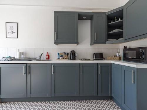 a kitchen with blue cabinets and a microwave at Longsands Beach, Apartment 4, Tynemouth in Tynemouth