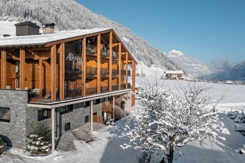 a wooden house in the snow with a mountain at Hotel Alpenhof in Grossarl