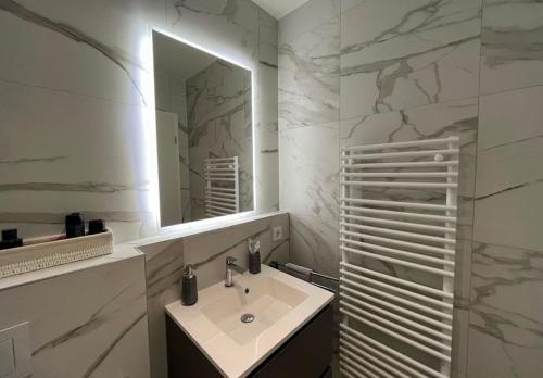 a white bathroom with a sink and a mirror at 1 bedroom with parking in center and a large terrace. in Luxembourg
