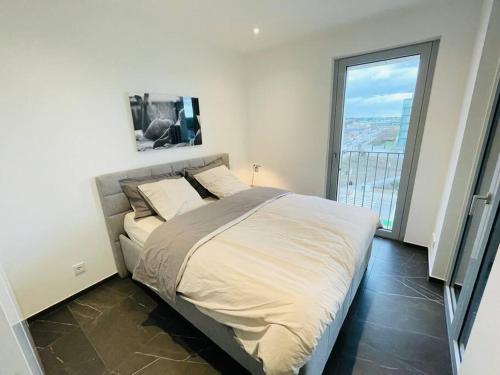 a bedroom with a large bed with a large window at 1 bedroom with parking in center and a large terrace. in Luxembourg
