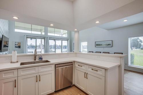 uma cozinha com armários brancos, um lavatório e janelas em Gorgeous Lakefront Townhome with Pool Access and Views em Montgomery